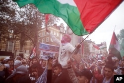 Demonstrators hold up flares, flags and placards during a pro Palestinian demonstration in London, Oct. 21, 2023.
