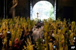 FILE—Catholics wave their palm fronds to commemorate Palm Sunday, April 2, 2023 in Manila, Philippines.