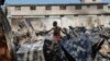 Seorang warga tampak mencari benda yang masih bisa diselamatkan dari sebuah toko peralatan mobil yang dibakar dalam kekerasan geng di Port-au-Prince, Haiti, pada 25 Maret 2024. (Foto: AP/Odelyn Joseph) 