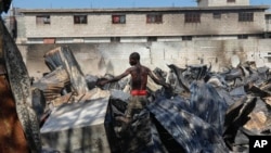 A man looks for salvageable items at a car mechanic shop that was set fire during gang violence in Port-au-Prince, Haiti, March 25, 2024. 