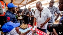 FILE - Former Ghana President John Dramani Mahama collects a ballot paper before casting his vote during the presidential and parliamentary election, in Bole Ghana, Wednesday, Dec. 7, 2016.