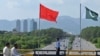 Seorang polisi berjaga di bawah bendera China dan Pakistan yang di pasang di sepanjang jalan menjelang kunjungan Wakil Perdana Menteri China He Lifeng, di Islamabad, Pakistan, 30 Juli 2023. (Foto: Farooq Naeem/AFP)