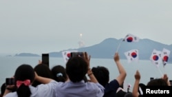 25일 한국 전라남도 고흥군 나로우주센터에서 '누리호' 3차 발사 직후 시민들이 태극기를 흔들며 환호하고 있다. 