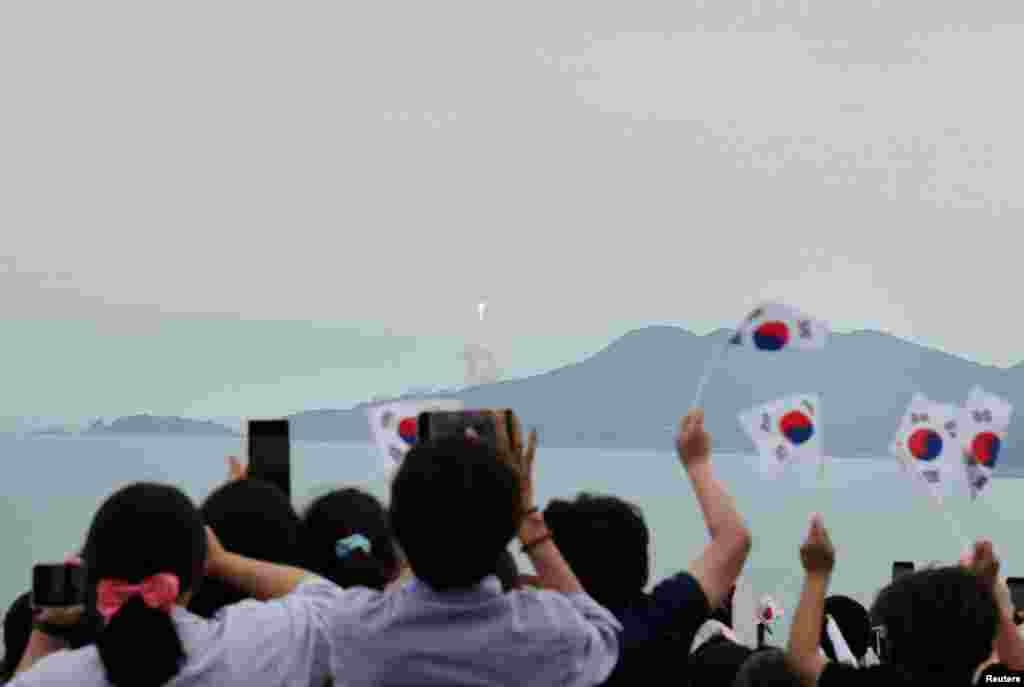 People watch the launch of South Korea’s homegrown Nuri space rocket in Goheung, South Korea. (Yonhap via Reuters)