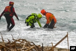 FILE - Rescuers recover a body after a migrant boat broke apart in rough seas, at a beach near Cutro, southern Italy, Feb. 26, 2023.