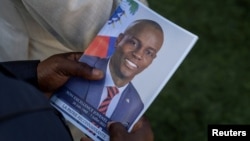 Una persona sostiene una foto del difunto presidente haitiano Jovenel Moise durante su funeral en la casa de su familia en Cabo Haitiano, Haití, el 23 de julio de 2021. Moise fue asesinado el 7 de julio de ese año.