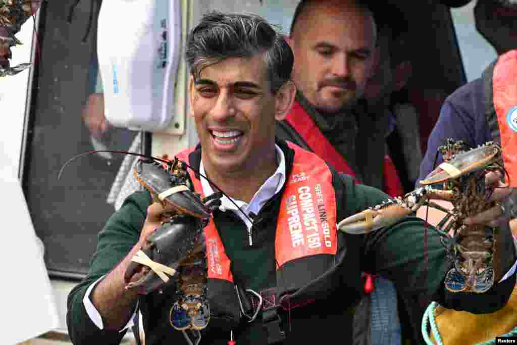 British Prime Minister Rishi Sunak reacts during his ride on a boat in the harbor with West Devon MP Geoffrey Cox, in Clovelly.