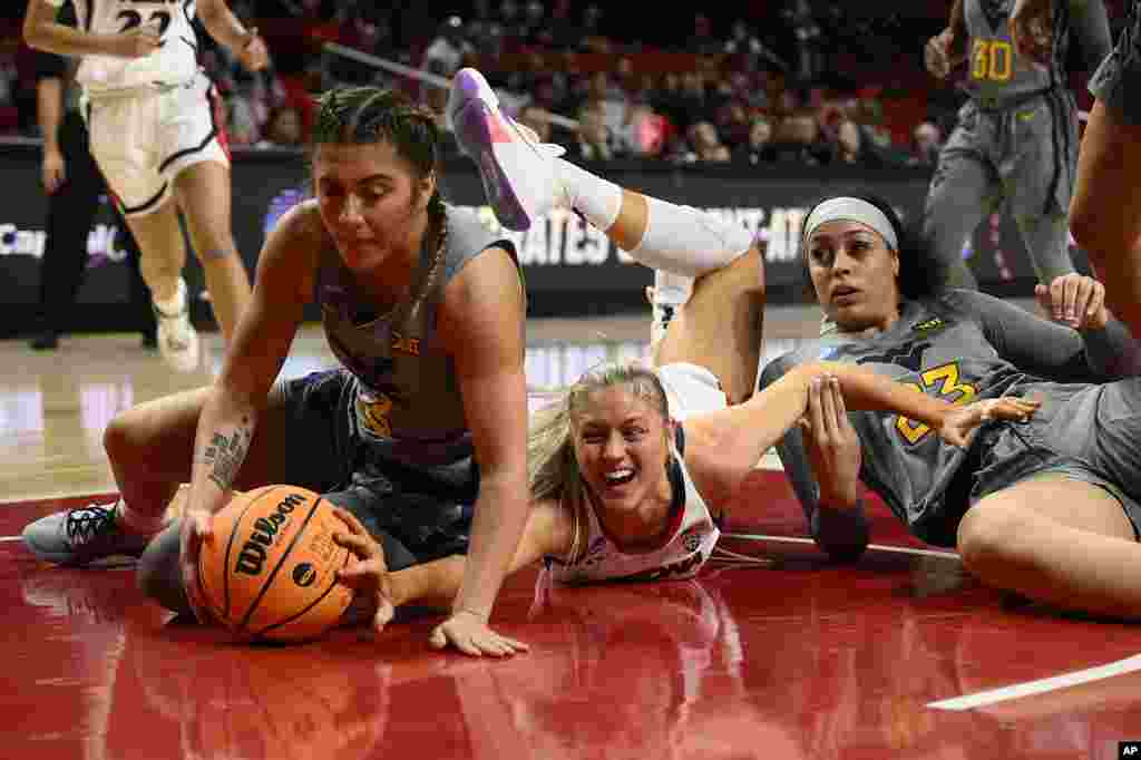 West Virginia guard Sarah Bates, left, and forward Isis Beh, right, battle for the ball against Arizona forward Cate Reese, center, in the first half of a first-round college basketball game in the NCAA Tournament, in College Park, Maryland.