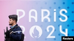 A French gendarme walks past the logo of the Paris 2024 Olympic and Paralympic Games in front of the National Assembly in Paris, May 2, 2024. 