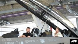 El presidente ucraniano, Volodymyr Zelenskyy, y la primera ministra danesa, Mette Frederiksen, sentados en un avión de combate F-16 en el hangar de la base aérea de Skrydstrup en Vojens, norte de Dinamarca, el 20 de agosto de 2023.