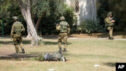 Soldados israelíes junto al cuerpo de un kibutz militante de Hamás, en Kfar Azza el martes 10 de octubre de 2023. Militantes de Hamás invadieron Kfar Azza el sábado pasado, donde muchos israelíes fueron asesinados y hechos cautivos.