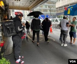 Migrantes se reúnen en la entrada del hotel Roosevelt en Manhattan, Nueva York, el 18 de septiembre de 2023. Muchos de los recién llegados trabajan como repartidores de comida para ganar dinero mientras esperan por la regularización de su estatus migratorio.