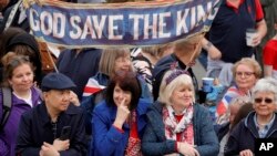 Orang-orang berkumpul saat menunggu untuk menyaksikan prosesi penobatan Raja Inggris Charles III dari Istana Buckingham ke Westminster Abbey, di London pada 6 Mei 2023. (Foto: via AP)