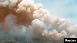 FILE - A New Brunswick aircraft drops a mix of water and fire retardant as it passes over the wildfire in Barrington Lake, Nova Scotia, Canada image released May 31, 2023.