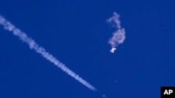 Na ovoj fotografiji koju je pružio Chad Fish, ostaci velikog balona plutaju iznad Atlantskog okeana, nedaleko od obale Južne Karoline, sa borbenim avionom i njegovim tragom ispod njega, 4. februara 2023. (Chad Fish preko AP-a)