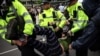 Anggota Kepolisan Metropolitan London menahan demonstran yang memblokade sebuah bus yang akan membawa para pencari suaka dari sebuha hotel di Peckham, di selatan London, pada 2 Mei 2024. (Foto: AFP/Henry Nicholls)