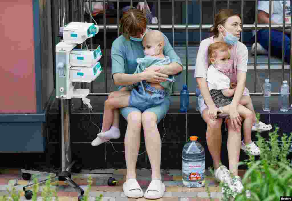 Women hold patients at Okhmatdyt children's hospital that was damaged during Russian missile strikes in Kyiv, Ukraine.
