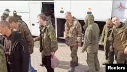 A still image from video, released by Russia's Defense Ministry April 10, 2023, shows what it claims to be Russian service personnel boarding a bus following an exchange of prisoners of war between Russia and Ukraine, at an unidentified location.