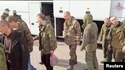 A still image from video, released by Russia's Defense Ministry April 10, 2023, shows what it claims to be Russian service personnel boarding a bus following an exchange of prisoners of war between Russia and Ukraine, at an unidentified location.