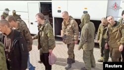 A still image, released by Russia's Defence Ministry, shows what it said to be captured Russian service personnel boarding a bus following an exchange of prisoners of war at an unknown location, in this image taken from footage released April 10, 2023.