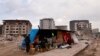 A family sits in an improvised shelter after their apartment building collapsed in an earthquake, in Antakya, southeastern Turkey, Feb. 21, 2023.