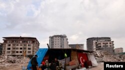 Sebuah keluarga duduk di tempat berlindung sementara, setelah bangunan mereka runtuh akibat gempa terbaru yang melanda Antakya, Turki tenggara, 21 Februari 2023. 