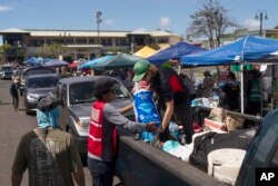 Volunteers work at a food distribution center set up in the parking lot of a shopping mall in Lahaina, Hawaii, Aug. 16, 2023.