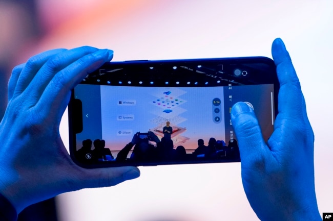 A person takes a cellphone video as Microsoft CEO Satya Nadella speaks during a showcase event of the company's AI assistant, Copilot, at Microsoft headquarters, Monday, May 20, 2024, in Redmond, Wash. (AP Photo/Lindsey Wasson)