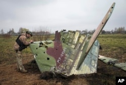 Украинский военный осматривает фрагмент российского штурмовика Су-25, сбитого у села Колонщина в Киевской области. Апрель 2022.