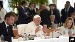 French President Emmanuel Macron, left, and Italy's Prime Minister Giorgia Meloni, right, listen to Pope Francis at the 50th G7 summit at Borgo Egnazia, southern Italy, June 14, 2024.