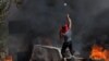 Seorang warga Palestina melempar batu di tengah bentrokan dengan tentara Israel, menyusul penyerangan yang dilakukan warga Israel yang menduduki Tepi Barat terhadap desa Umm Safa di dekat Ramallah, Tepi Barat, pada 24 Juni 2023. (Foto: Reuters/Mohamad Torokman)