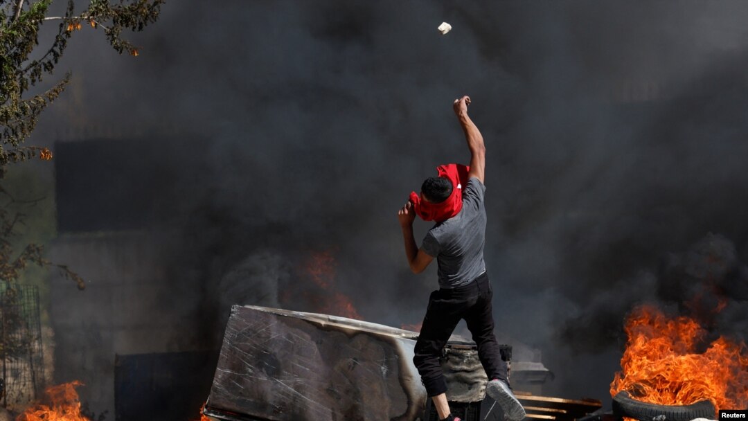Seorang warga Palestina melempar batu di tengah bentrokan dengan tentara Israel, menyusul penyerangan yang dilakukan warga Israel yang menduduki Tepi Barat terhadap desa Umm Safa di dekat Ramallah, Tepi Barat, pada 24 Juni 2023. (Foto: Reuters/Mohamad Torokman)