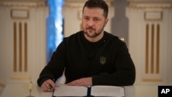 Presiden Ukraina Volodymyr Zelenskyy menandatangani dokumen di Kyiv, 12 Januari 2024. Zelenskyy menuju ke Swiss pada 15 Januari 2024. (Foto: AP)