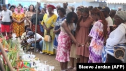 Des parents et des amis se recueillent près de fleurs et de bougies en mémoire des disparus du naufrage d'un ferry au port de Libreville, le 13 mars 2023.