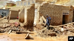 An Afghan man collects his belongings from his damaged home after heavy flooding in Ghor province in western Afghanistan, May 18, 2024. 