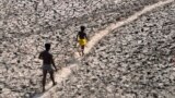 FILE - A man and a boy walk across a dried-up bed of river Yamuna in New Delhi, India, May 2, 2022. (AP Photo/Manish Swarup, File)