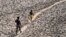 FILE - A man and a boy walk across a dried-up bed of river Yamuna in New Delhi, India, May 2, 2022. (AP Photo/Manish Swarup, File)