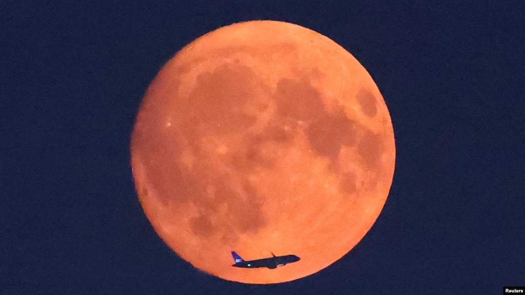 An aircraft passes in front of the moon, with a red glow attributable to smoke particles carried in the upper atmosphere from North American wildfires, a day ahead of the full super moon, as seen from Parliament Hill in London, Britain, August 18, 2024. (REUTERS/Toby Melville)