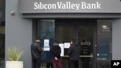 Sejumlah nasabah memperhatikan pengumuman yang ditempel di pintu masuk Bank Silicon Valley di Santa Clara, California, Jumat, 10 Maret 2023. (Foto: Jeff Chiu/AP Photo)