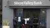 People read signs posted outside of an entrance to Silicon Valley Bank in Santa Clara, California, March 10, 2023.