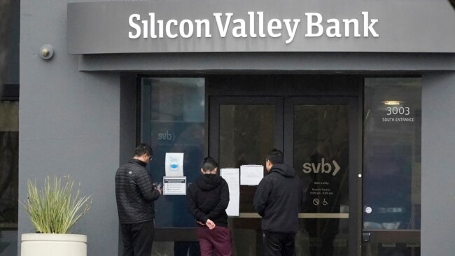 People read signs posted outside of an entrance to Silicon Valley Bank in Santa Clara, California, March 10, 2023.