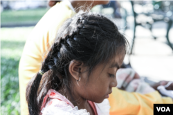 កូនស្រីអាយុ ៦ ឆ្នាំរបស់អ្នកស្រី ឆេង លក្ខិណា អង្គុយលេងទូរសព្ទ ខណៈរង់ចាំរ៉ឺម៉កកង់បីនៅក្រៅមន្ទីរពេទ្យគន្ធបុប្ផា ក្នុងរាជធានីភ្នំពេញ កាលពីថ្ងៃទី ១ ខែមីនា ឆ្នាំ ២០២៣។ (ទែន សុខស្រីនិត/វីអូអេ)