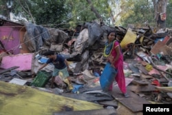 FILE - Dharmender Kumar and his wife Khushboo Devi collect usable items from the rubble of their house during a demolition drive by the authorities at a slum area near the upcoming summit venue in New Delhi, June 1, 2023. ( REUTERS/Adnan Abidi)