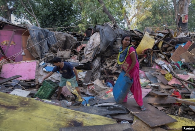 FILE - Dharmender Kumar and his wife Khushboo Devi collect usable items from the rubble of their house during a demolition drive by the authorities at a slum area near the upcoming summit venue in New Delhi, June 1, 2023. ( REUTERS/Adnan Abidi)