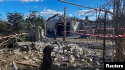 Local men inspect residential buildings damaged by a Russian missile strike in the village Obukhivka, Dnipropetrovsk region, Ukraine, Oct. 18, 2023.
