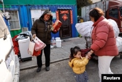 Wu Yonghou, 58, receives presents from a resident on Chinese Lunar New Year's Eve, at the recycling station where he and his wife work, in Beijing, China February 9, 2024. (REUTERS/Tingshu Wang)