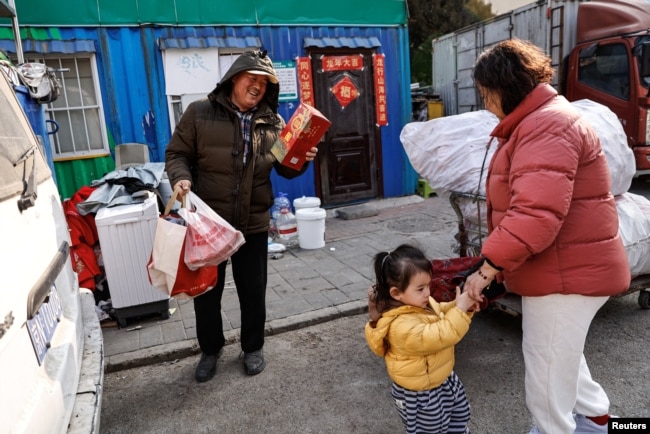 Wu Yonghou, 58, receives presents from a resident on Chinese Lunar New Year's Eve, at the recycling station where he and his wife work, in Beijing, China February 9, 2024. (REUTERS/Tingshu Wang)