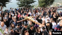 Christian worshipers take part in the Good Friday procession as they carry a cross with a Jesus Christ statue, in the town of Klayaa, southern Lebanon, March 29, 2024. 
