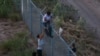 Мигранты преодолевают заграждание на границе Мексики и США. 