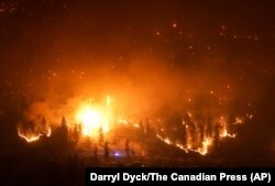 The McDougall Creek wildfire burns on the mountainside above lakefront homes in West Kelowna, Canada, Aug. 18, 2023.